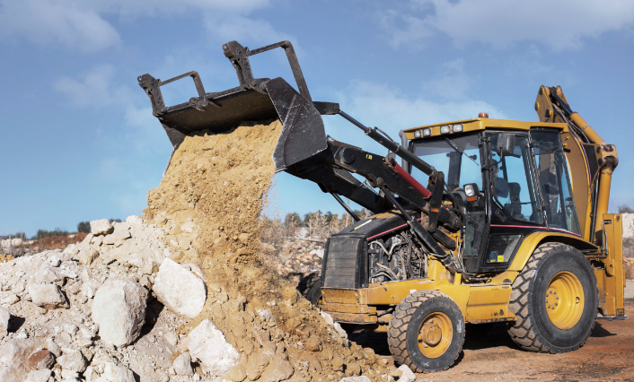 Backhoe clearing concrete rubble during a structural demolition project in Los Angeles County